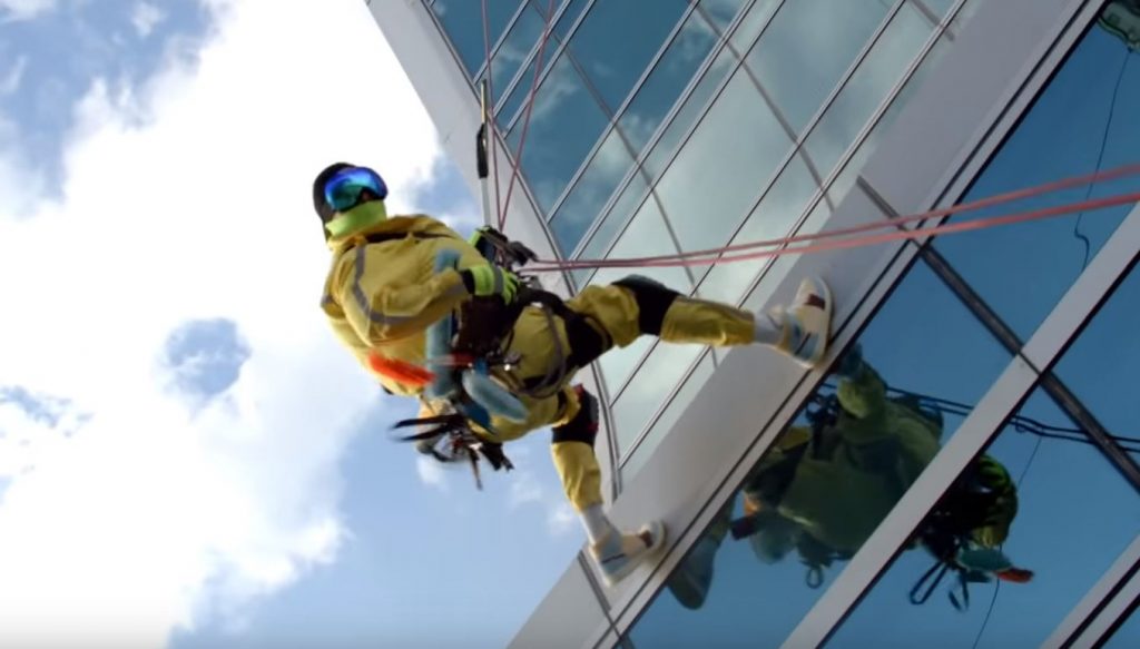 Man repelling down exterior of building